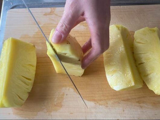 パイナップルの芯を包丁で切り落としている様子