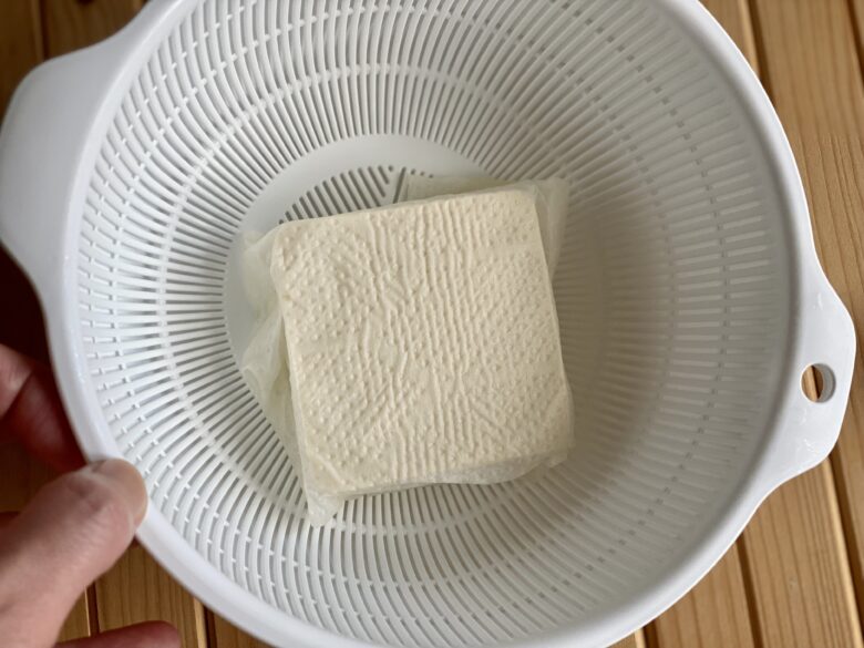 キッチンペーパーで包んでザルで水切りしている絹ごし豆腐