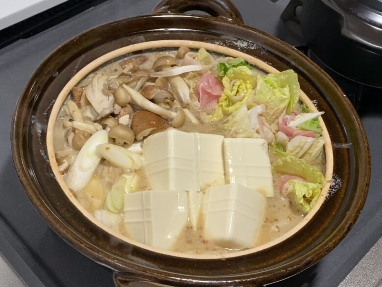 土鍋で豚肉と白菜の豆乳ごまみそ鍋を煮込んでいる様子