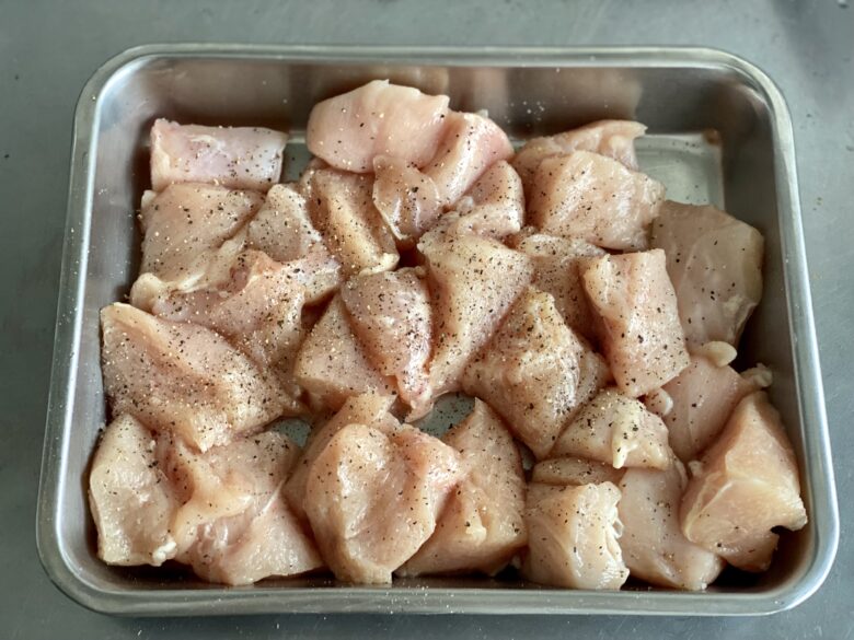 ステンレスバットにあるひと口大に切って塩・胡椒をふった鶏むね肉