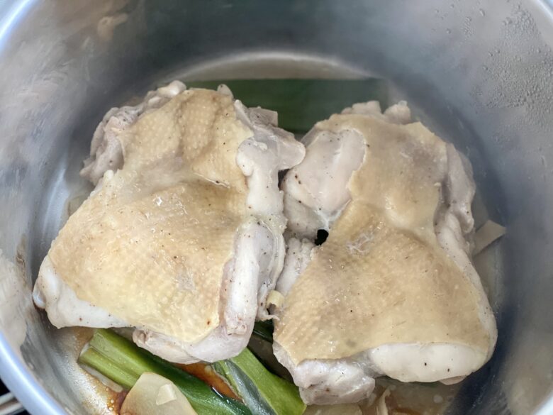 ステンレス鍋で青ねぎとしょうがを入れて蒸した鶏もも肉