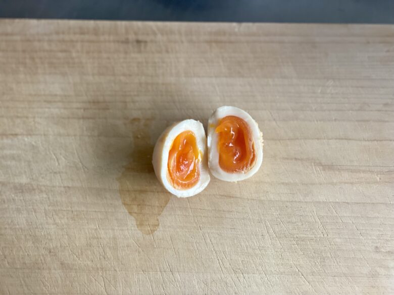 木製まな板の上で半分に切ったみそ漬け半熟卵