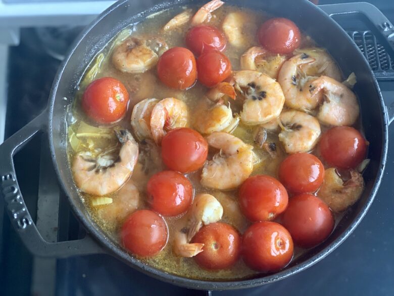トムヤムクン風スープカレーにプチトマトと炒めた海老を加えて煮込んでいる様子