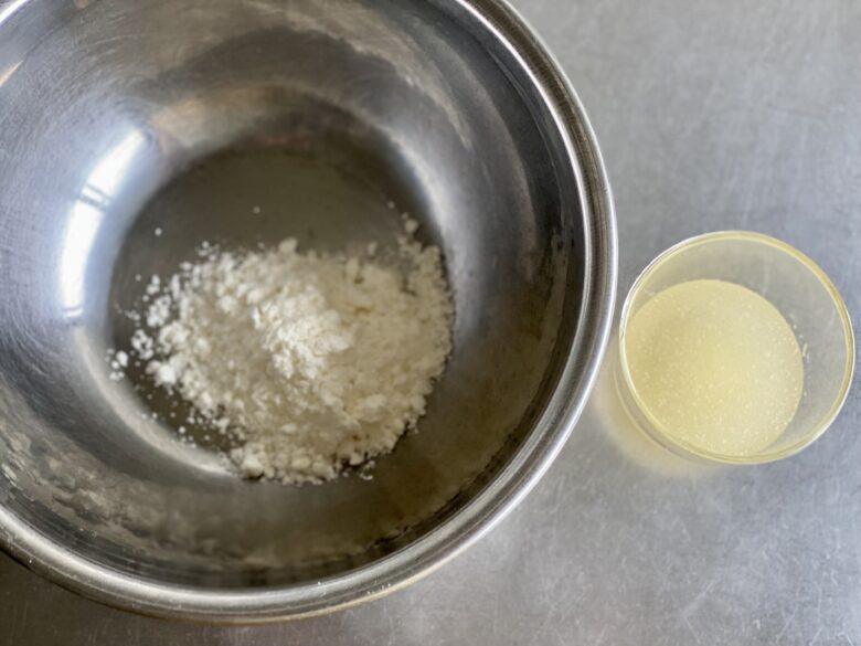 ガラスの器でふやかした粉ゼラチンとステンレスボウルに入れた杏仁霜（きょうにんそう）