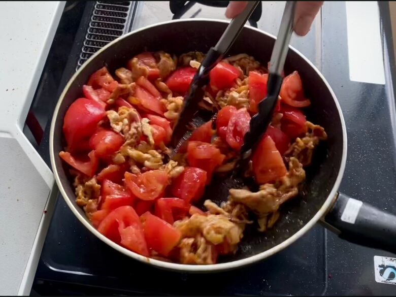 フライパンで炒めている豚肉とトマト
